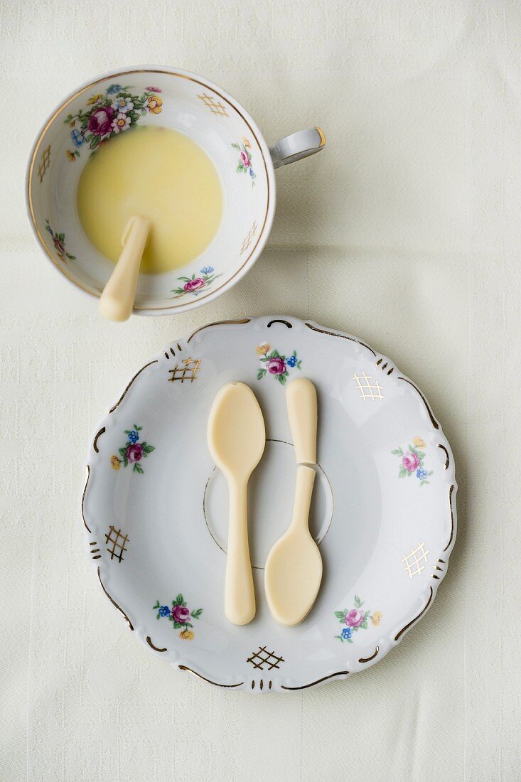White chocolate spoons on a plate and a cup of hot white chocolate