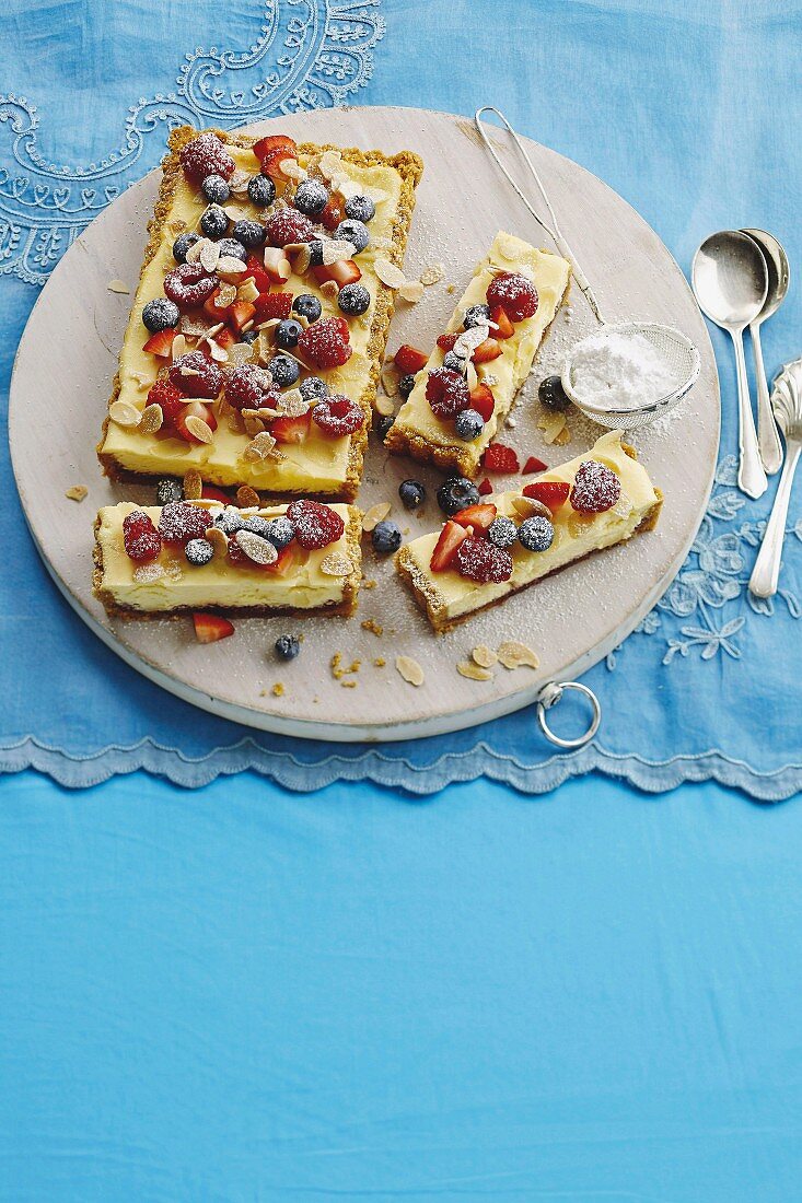 Bakewell Cheesecake mit Beeren, Mandelblättchen und Puderzucker