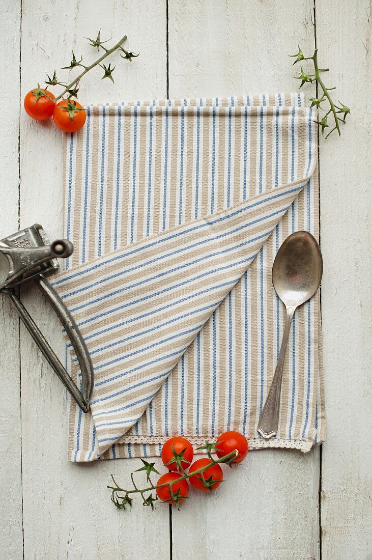 A kitchen towel, a spoon, cherry tomatoes and a cheese grater