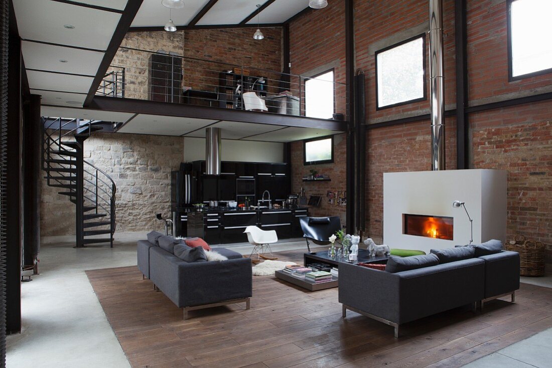 Elegant lounge area and open-plan kitchen in loft apartment with brick and stone walls