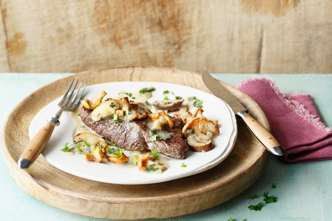 Fried beef steaks with fresh answer mushrooms in a creamy sauce
