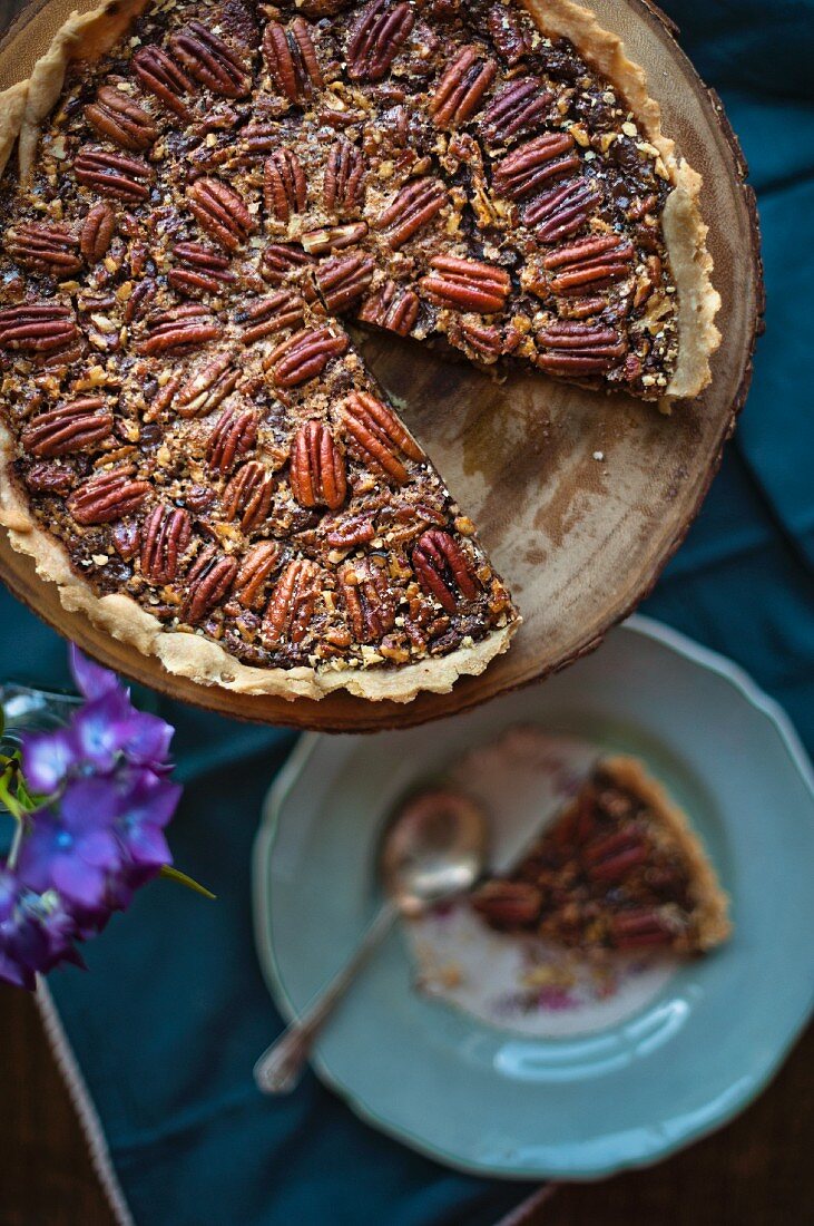 A pecan nut tart, sliced, on a cake stand