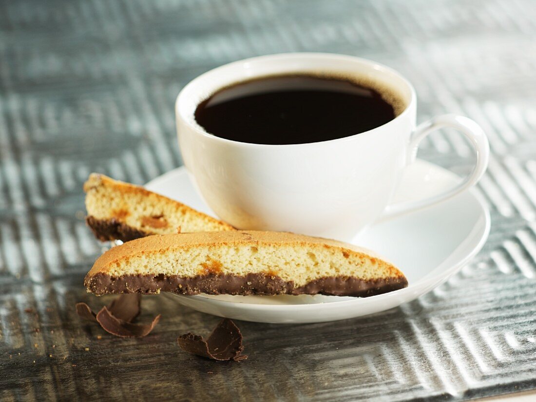 Mandelbiscotti mit Schokolade neben Kaffeetasse