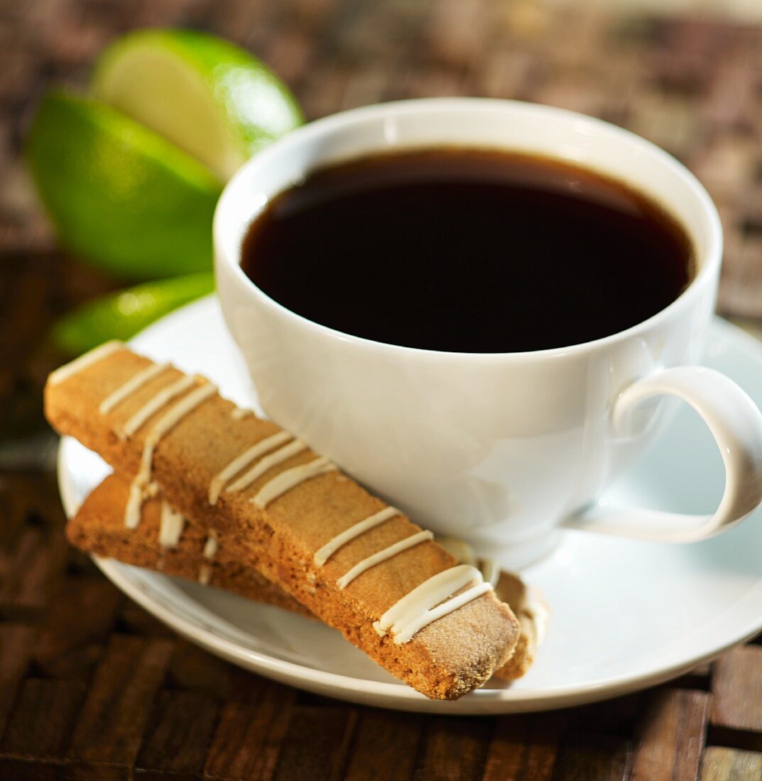 Biscotti with a lime glaze next to a cup of coffee