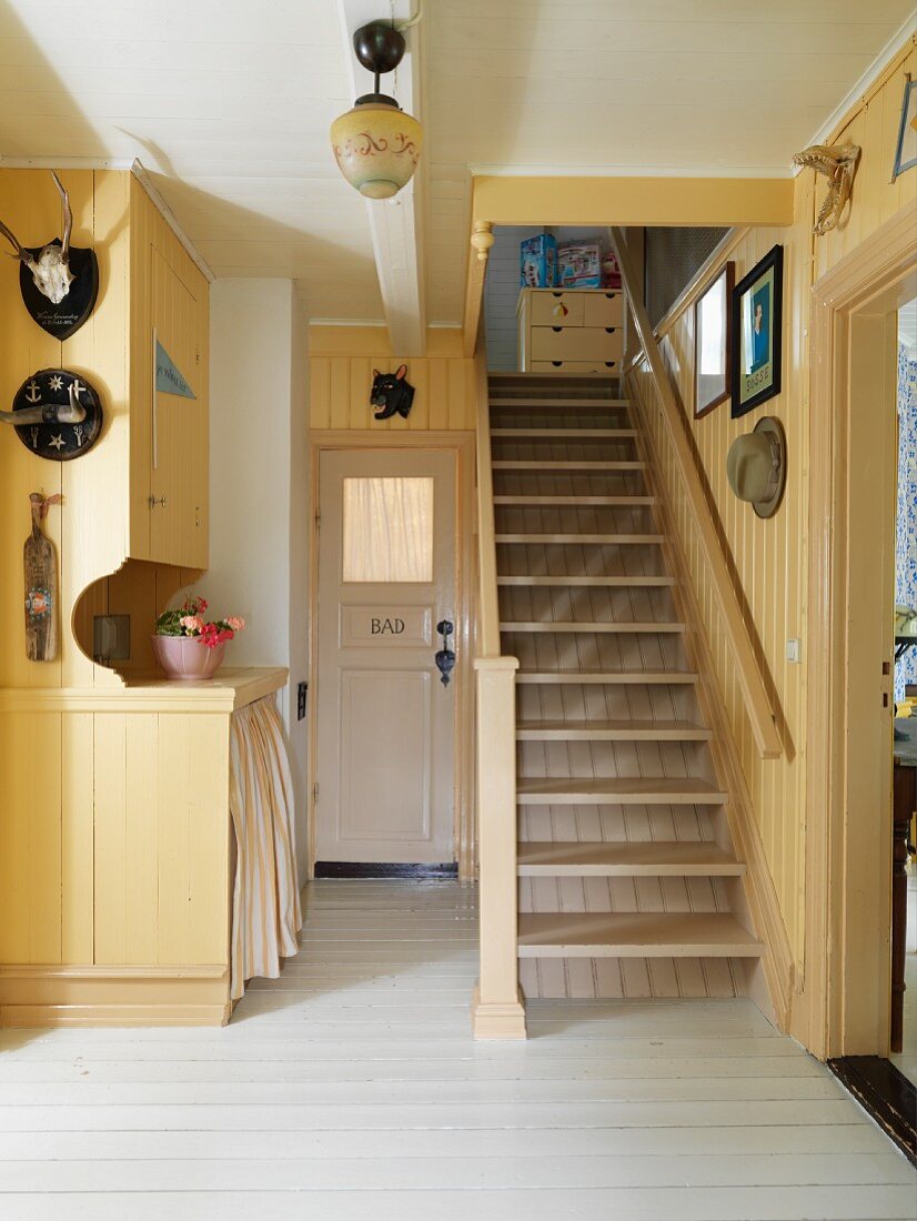Wood-clad foyer painted pale yellow with staircase in old country house