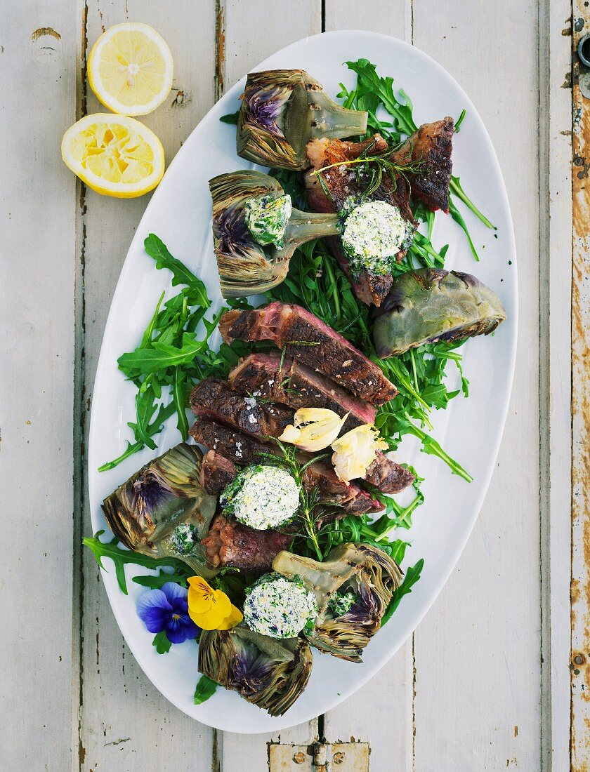 Grilled artichokes with herb and flower butter and a T-bone steak