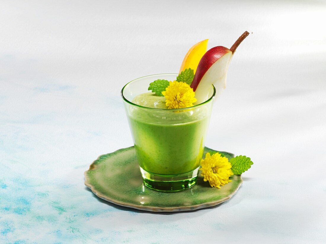 A mango and spinach smoothie garnished with flowers