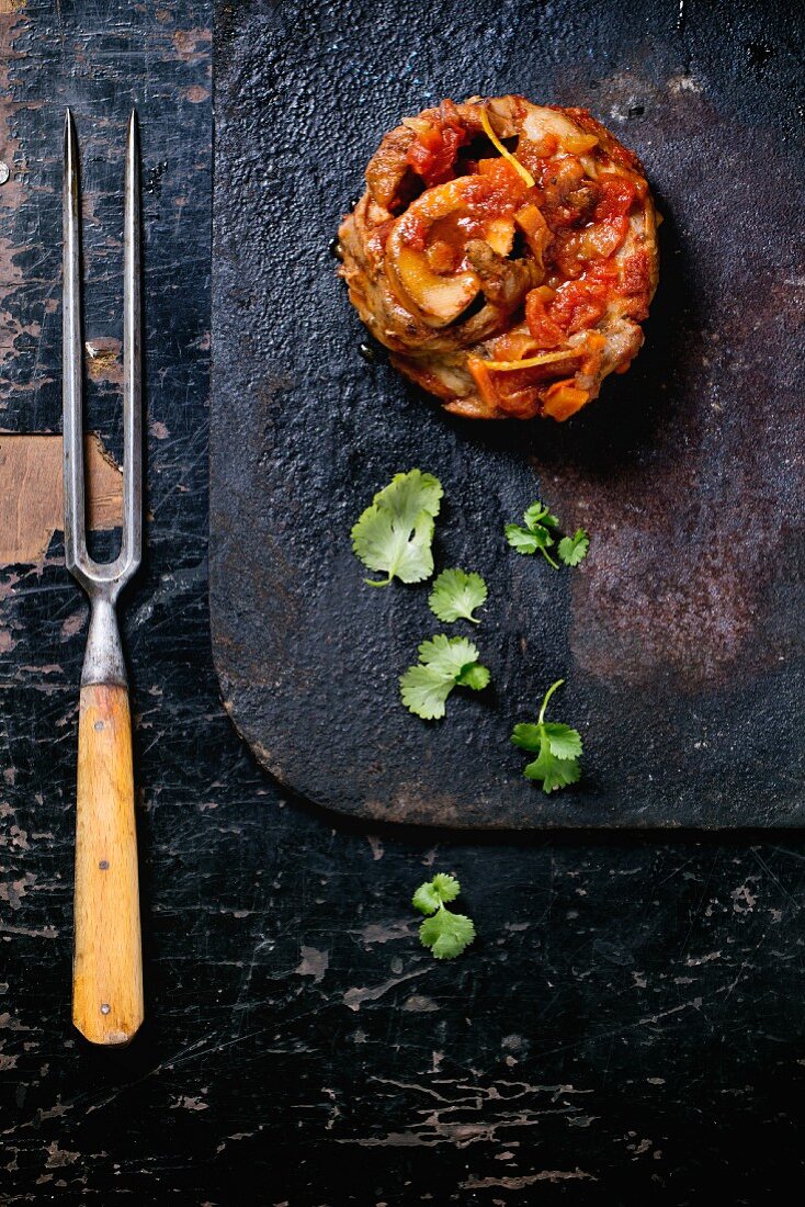 Ossobuco Milanese mit frischer Petersilie auf schwarzem Tisch