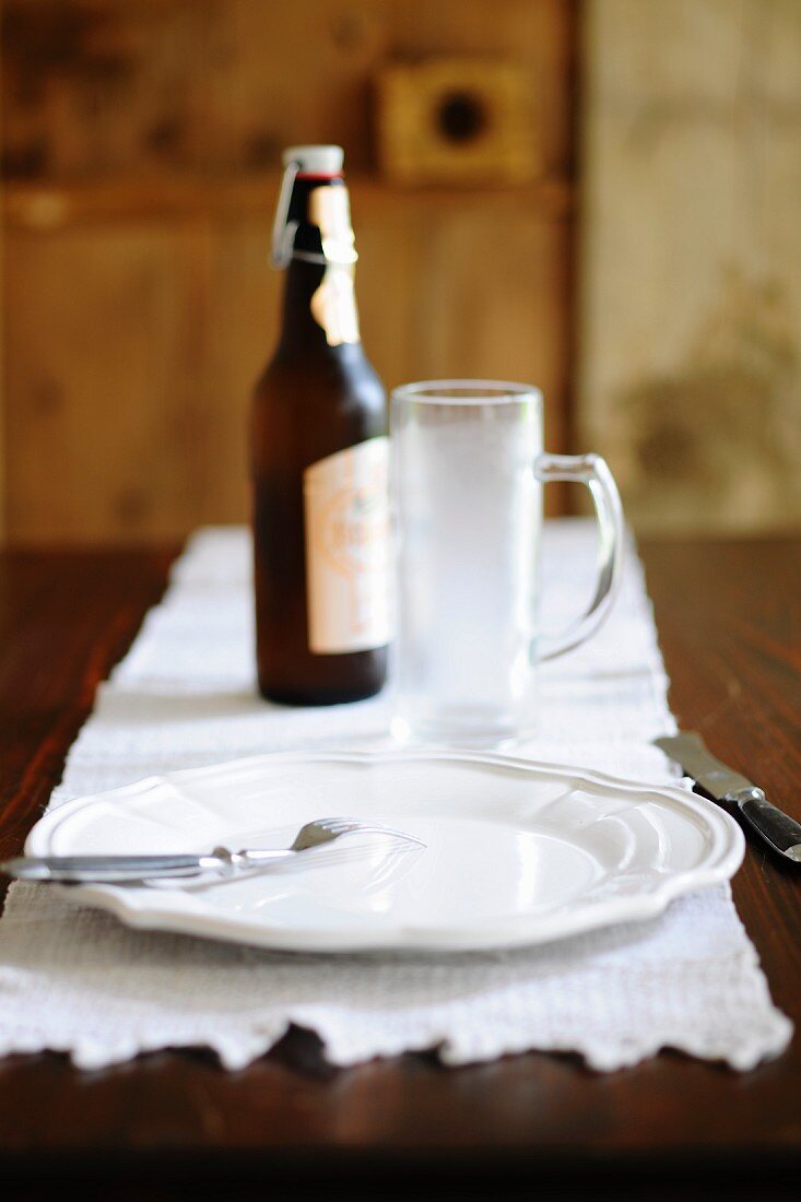 A place setting with a beer glass and bottle of beer