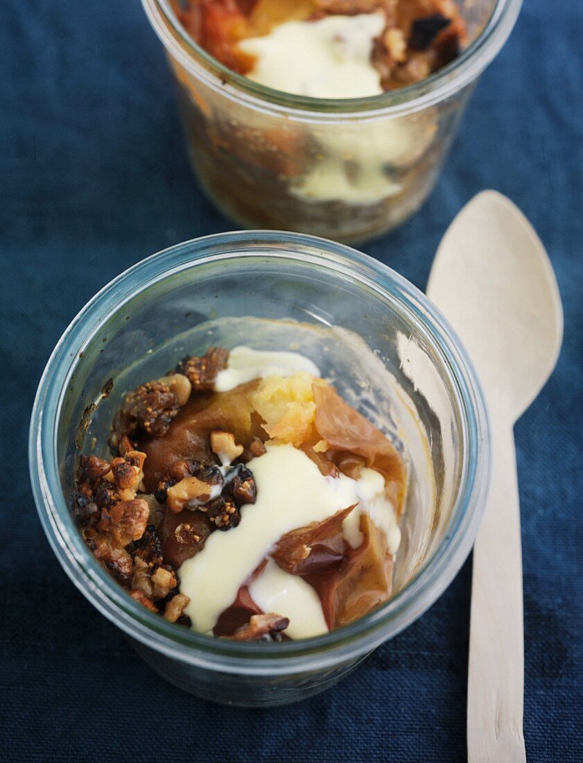 Baked apples in glasses with a wooden spoon on a dark linen surface