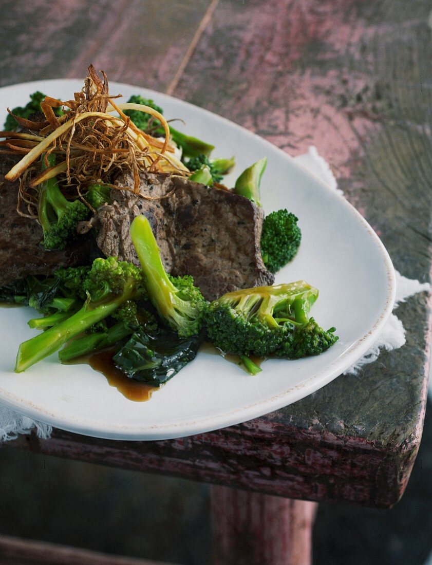 Broccoli with ginger and beef on a pink wooden table