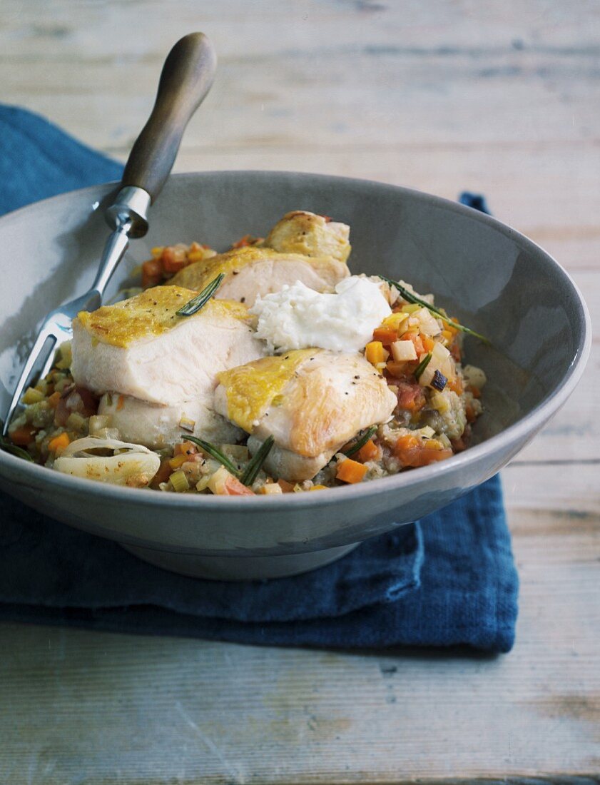 Unripe spelt grain risotto with chicken breast on a grey plate with a fork