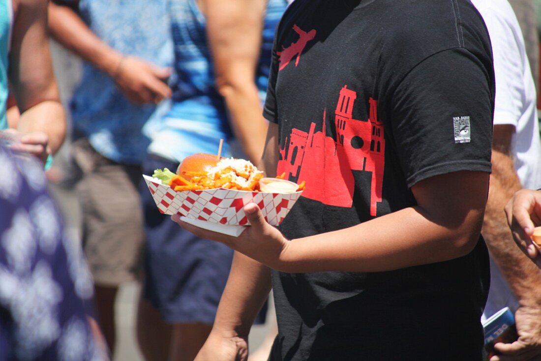 Mann hält Slider und Pommes frites beim Food Truck Festival in Kalifornien, USA