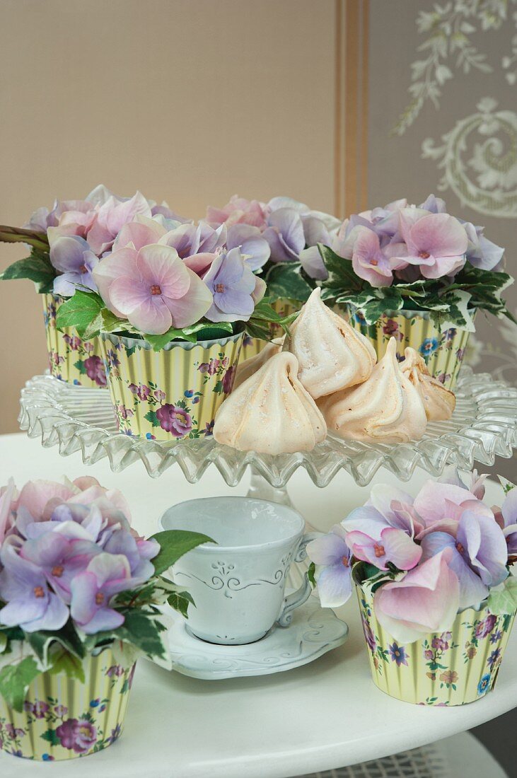 Violette Hortensien in Töpfen mit bedruckten Papierhüllen auf Kuchenständer