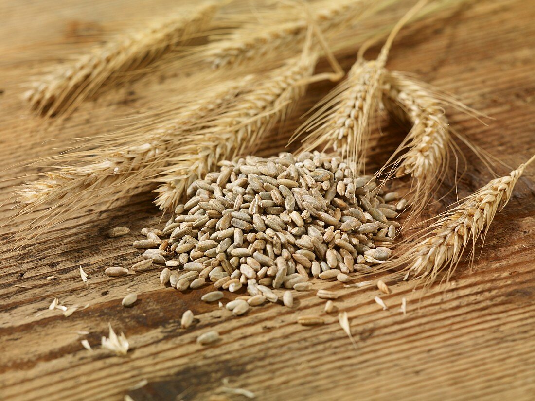 Rye seeds and ears of rye on a wooden surface
