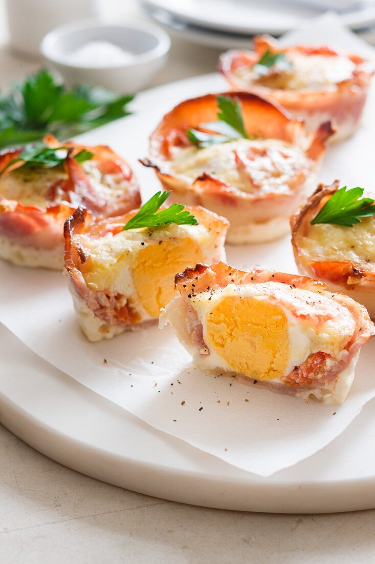 Baked eggs wrapped in bacon, whole and halved