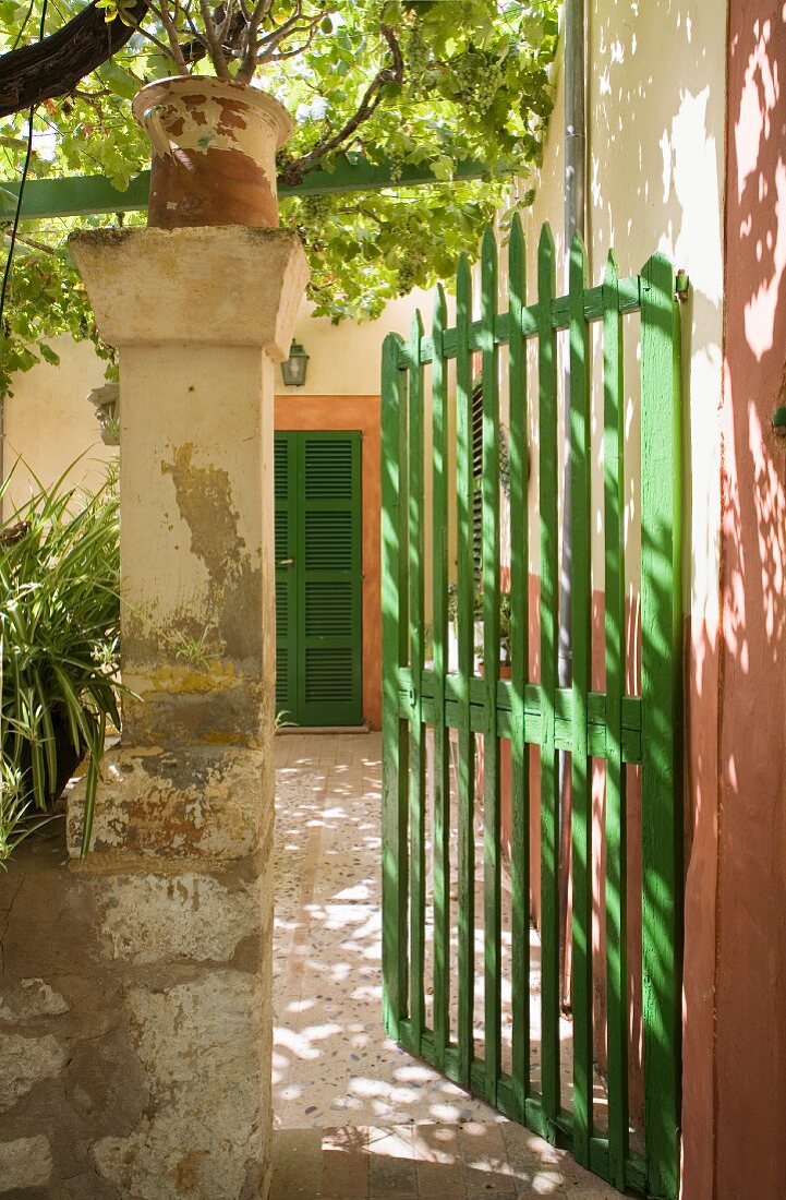 Green-painted gate and view of Mediterranean front door with ochre surround