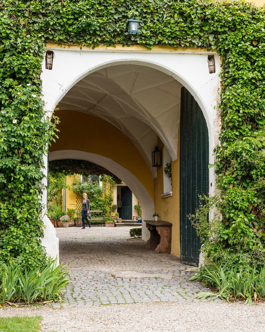 Arched entrance with vaulted ceiling in ivy-covered villa façade