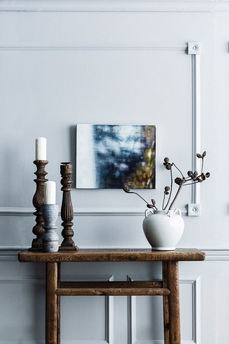 Kerzenhalter und Vase mit Trockenblumen auf rustikalem Konsolentisch aus Holz