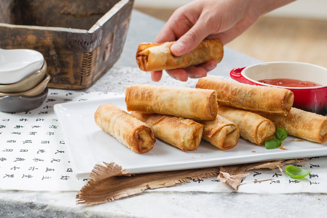 Hand reaching for a vegan spring roll