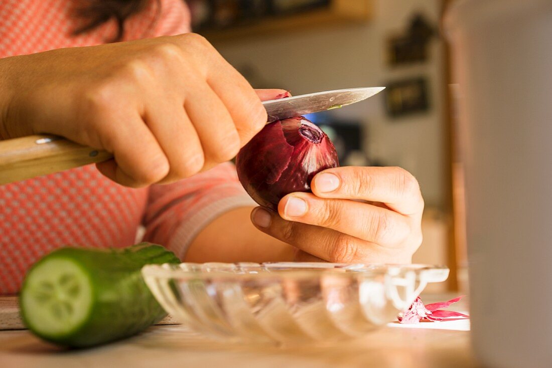 A woman peeling a red onion