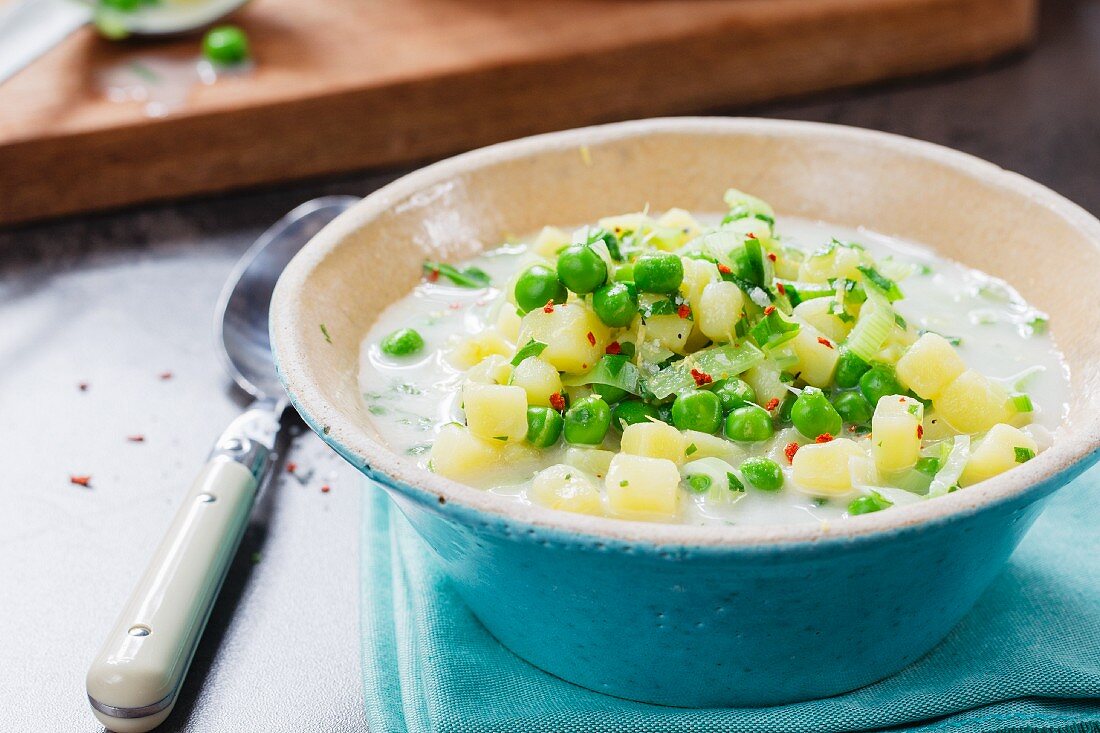 Vegan potato soup with peas, dandelions and vegetable cream