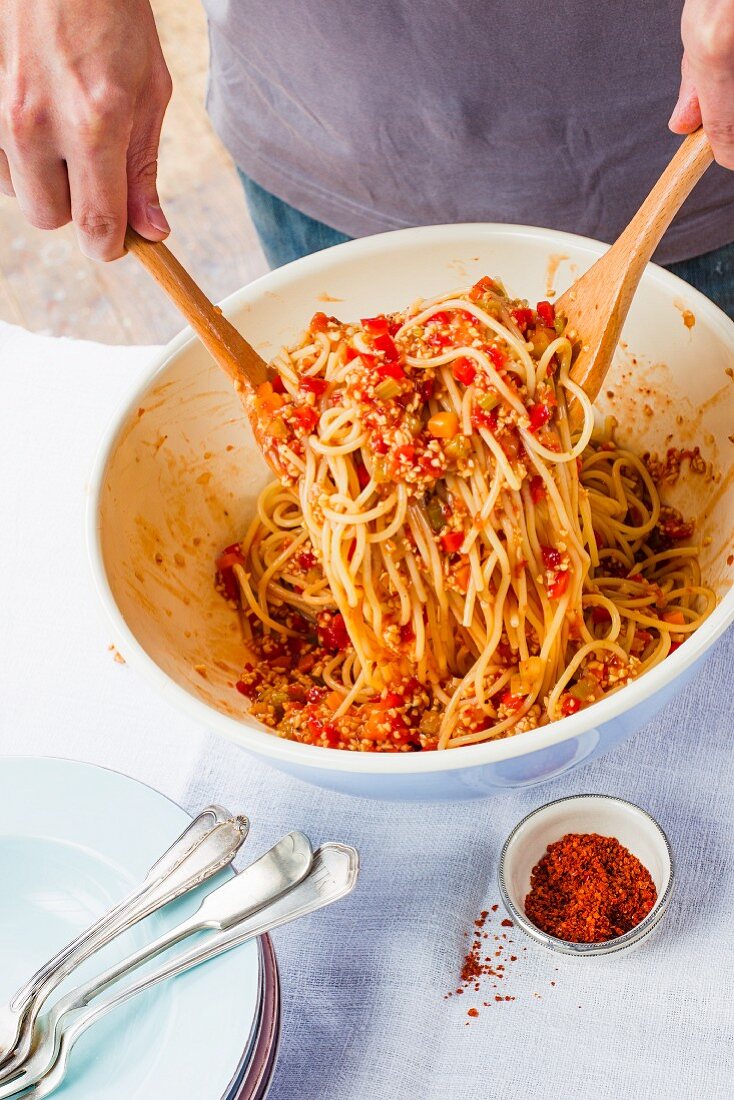 Vegane Spaghetti mit Soja-Gemüse-Sugo in einer Schüssel vermischen