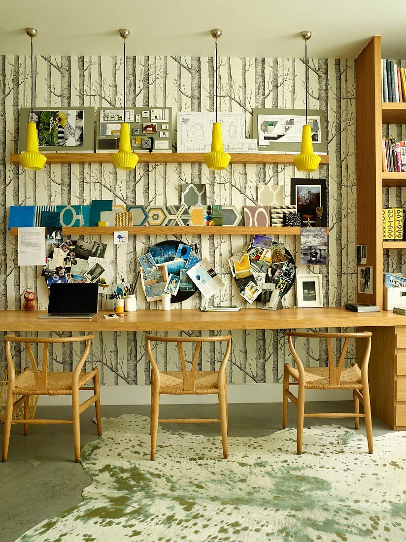 Long table and classic wooden chairs against study wallpaper with pattern of tree trunks