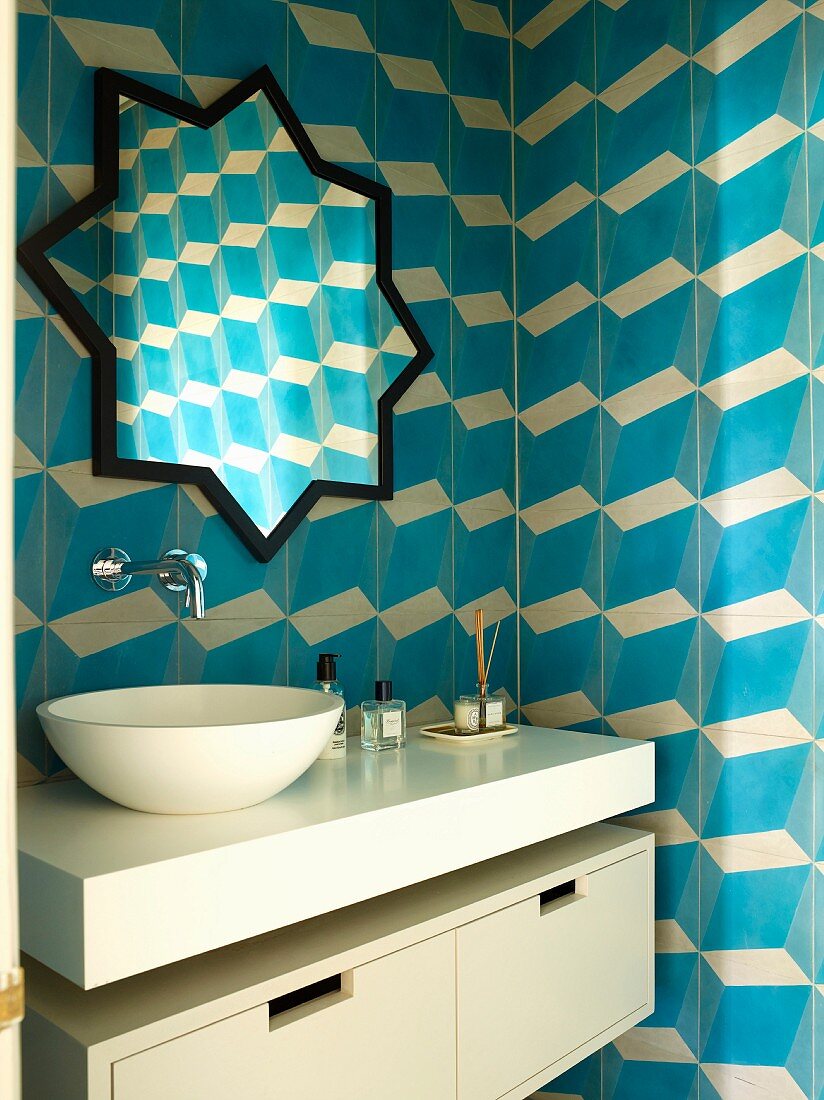 Modern washstand with countertop basin below star-shaped mirror on tiled wall with blue and white 3D pattern