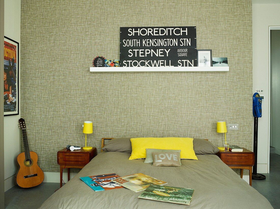 Double bed with taupe bed linen, yellow table lamps on delicate bedside cabinets and wallpapered wall