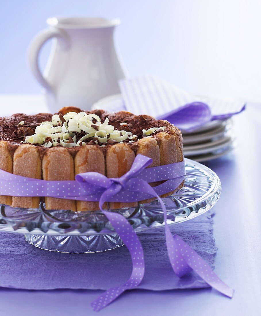 A chocolate cake made with sponge fingers decorated with a purple ribbon
