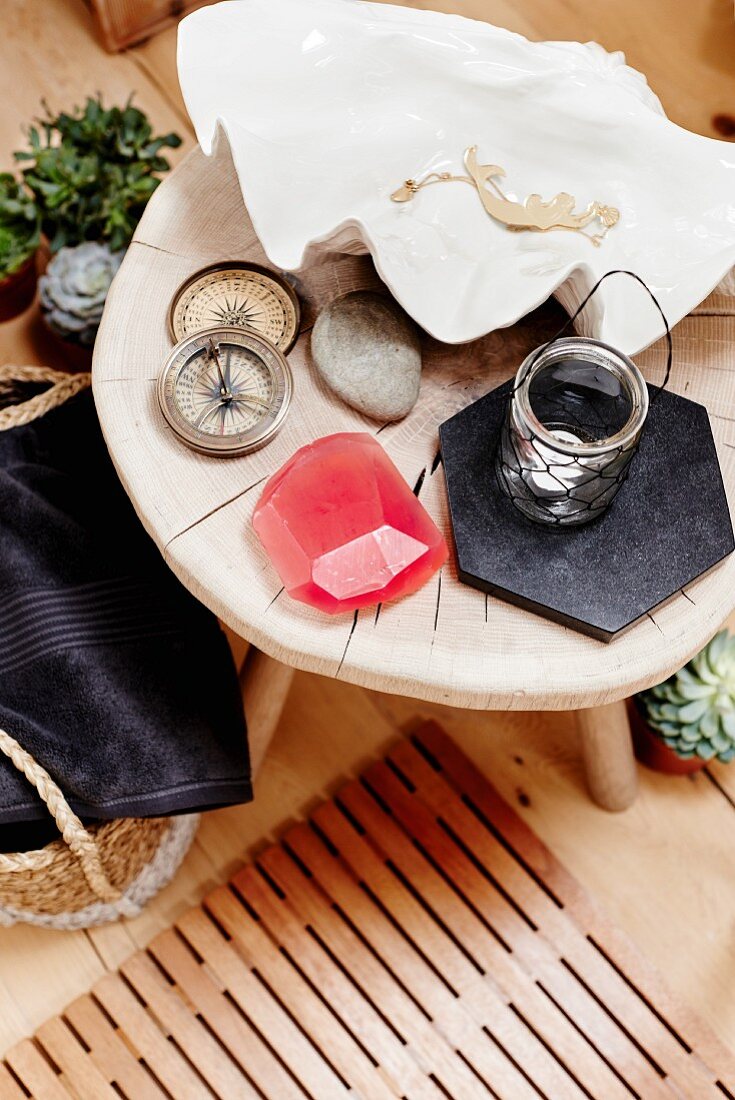 Compass and candle lantern next to large shell on rustic stool and wooden grate on floor