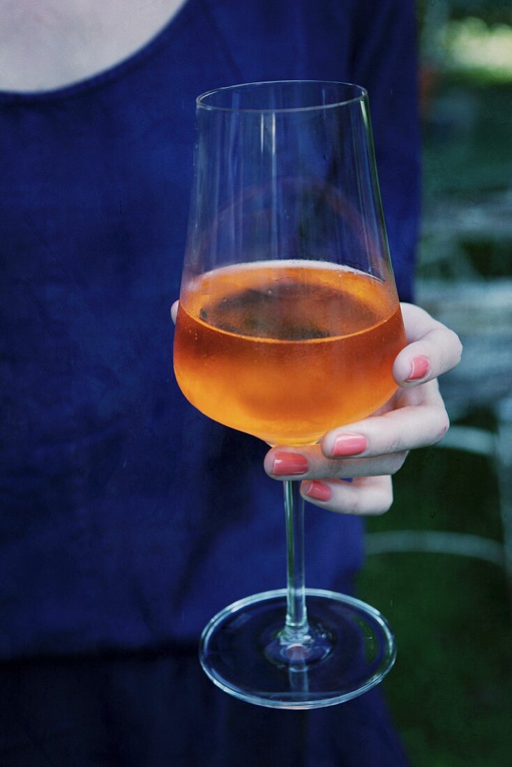 A woman holding a glass of Aperol Sprizz