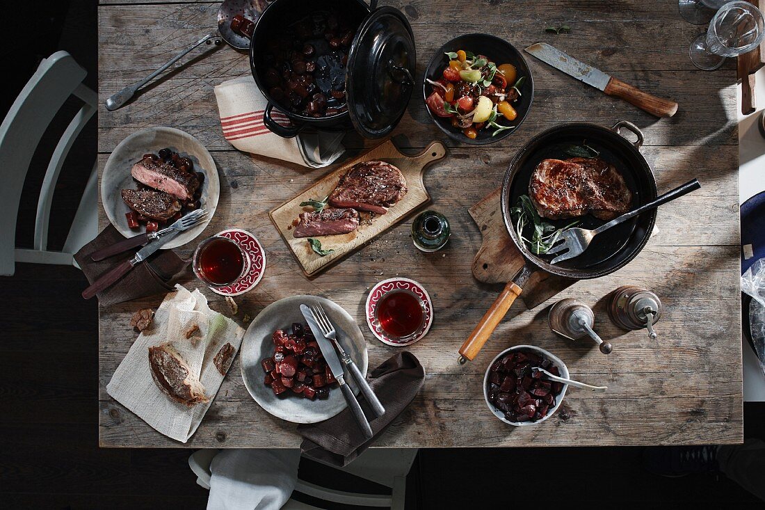 Gedeckter Tisch mit Tomatensalat, Steak und Eintopf