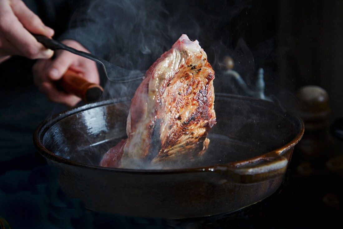 A steak being fried in a pan