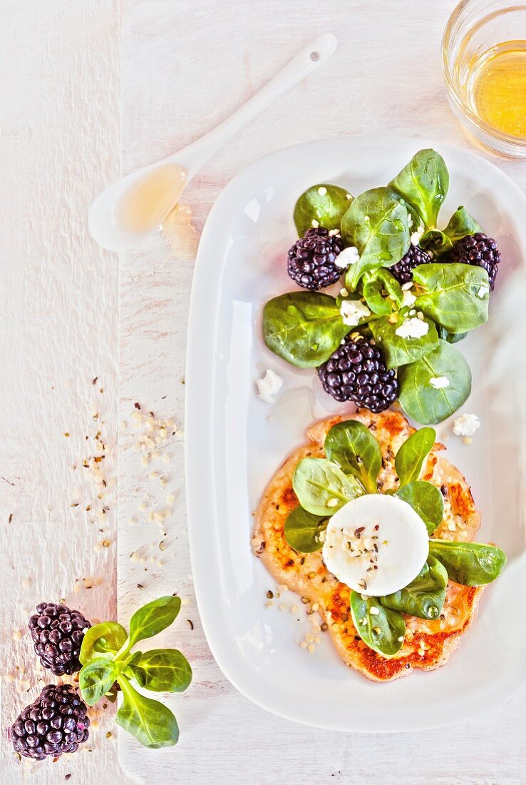 Sesame seed cakes with goat's cream cheese, lamb's lettuce and blackberries