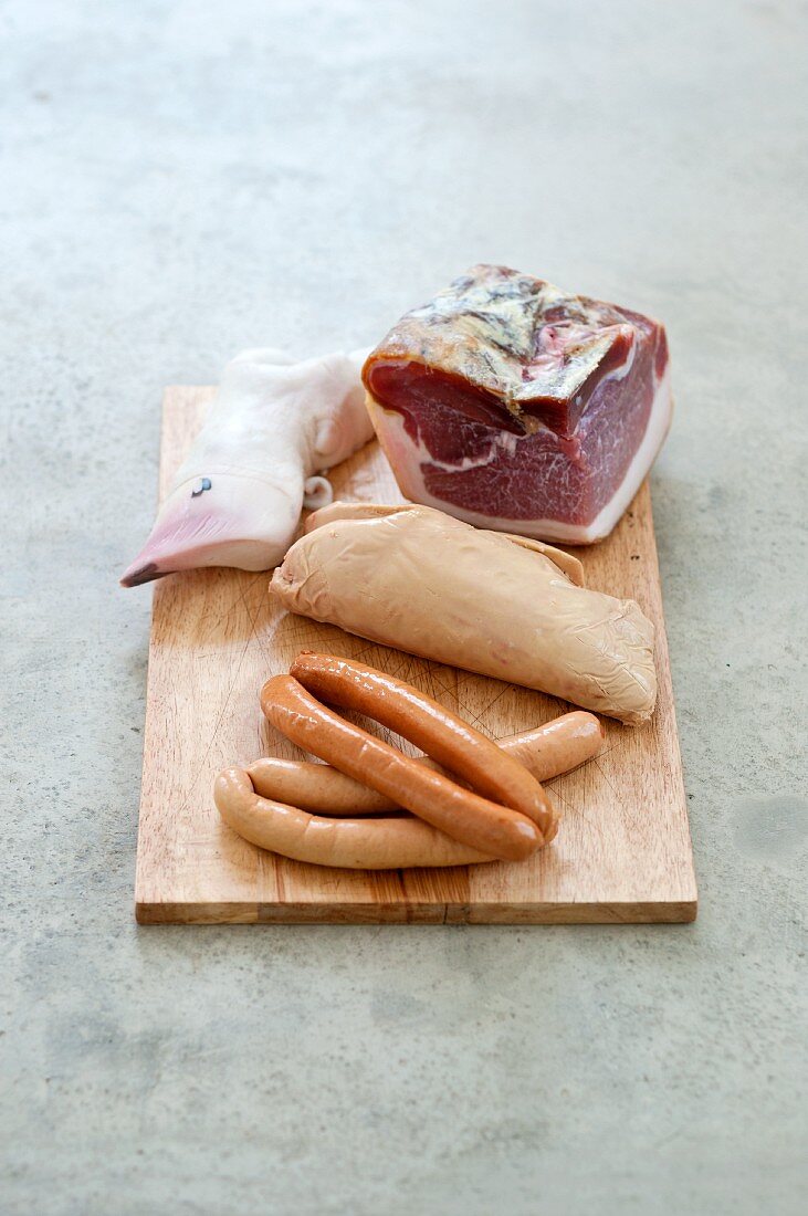 Various types of sausages and goose liver on a chopping board