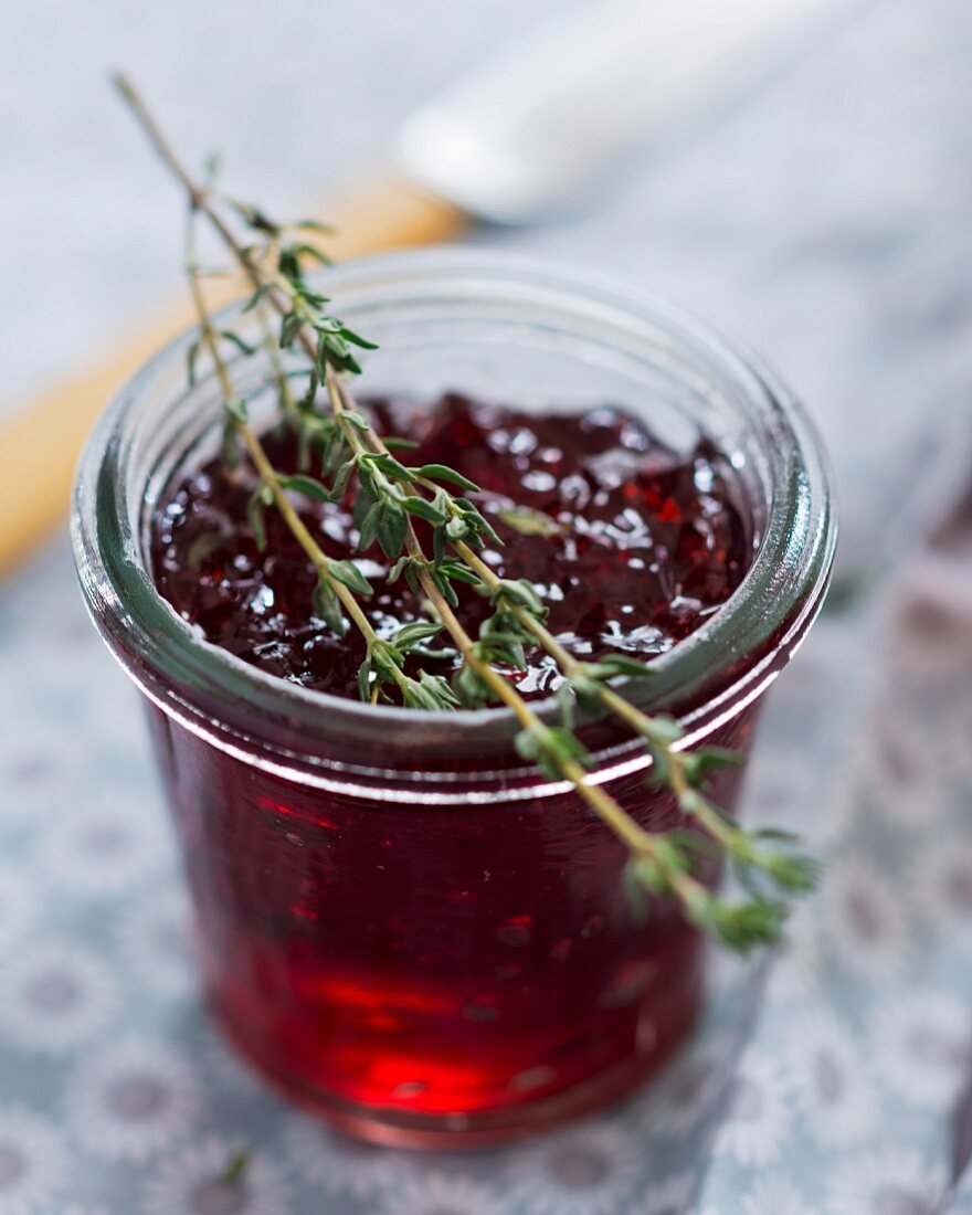 A jar of cherry jelly with thyme