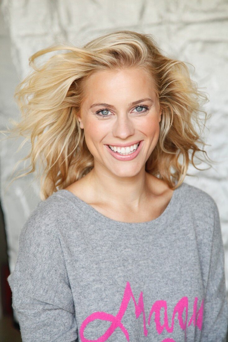 A blonde woman wearing a grey jumper with the word 'Magic' in pink