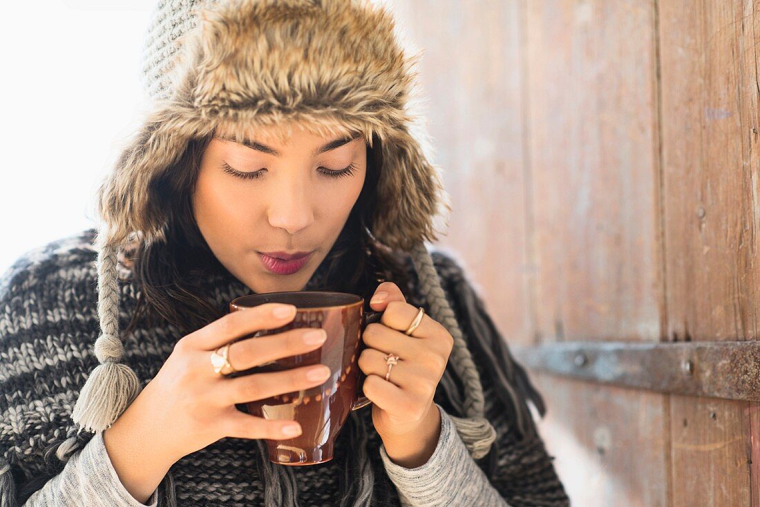 A woman wearing a fur hat holding a cup of coffee
