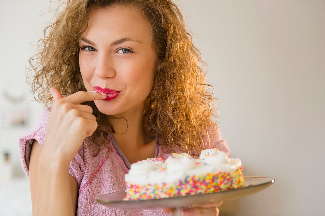 A young woman tasting a birthday cake