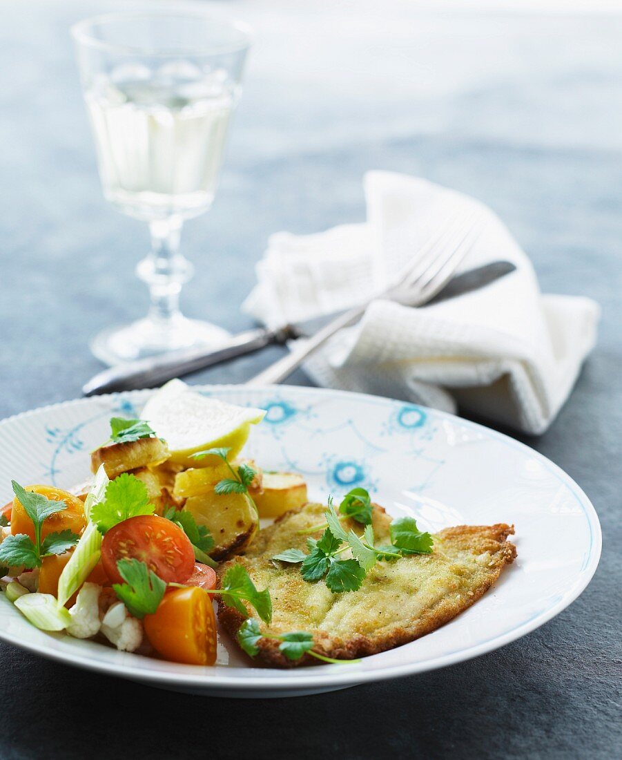 Breaded plaice fillets with fried potatoes and tomatoes