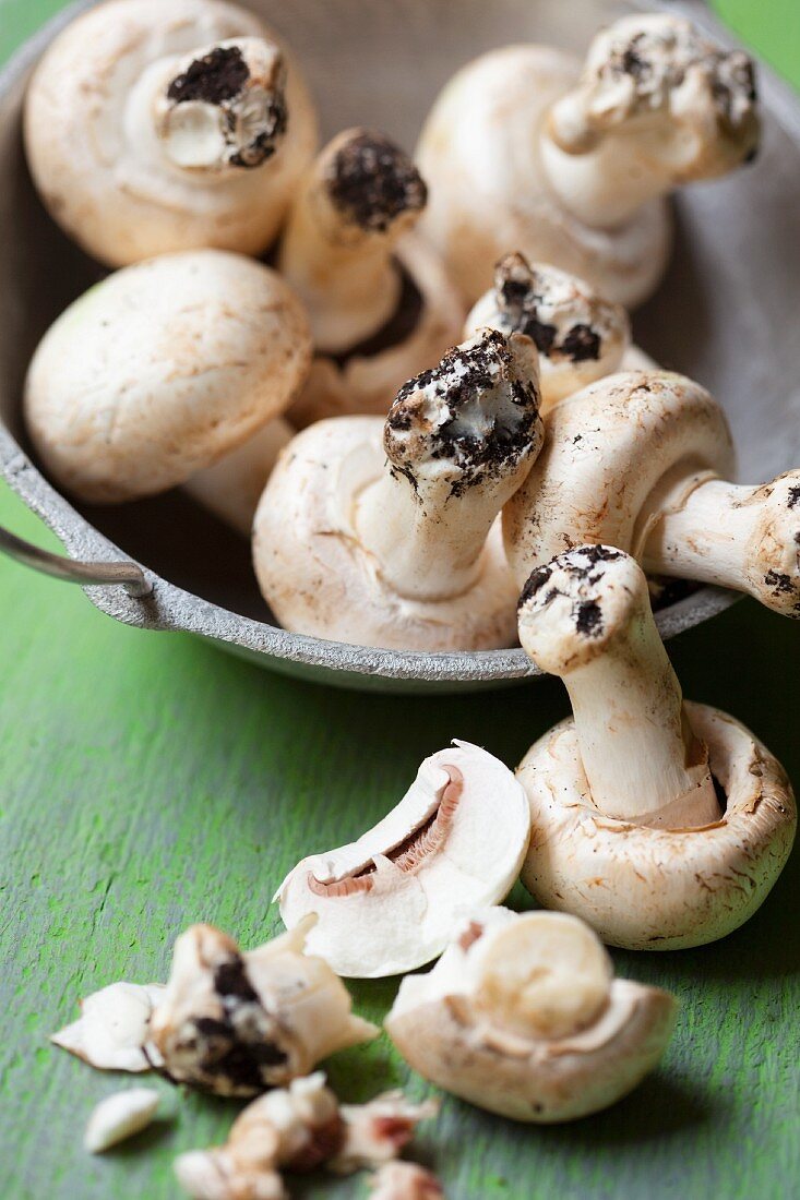 Fresh mushrooms with soil in and in front of a bowl