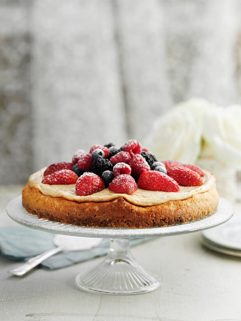 Cheesecake with vanilla cream and berries on a cake stand