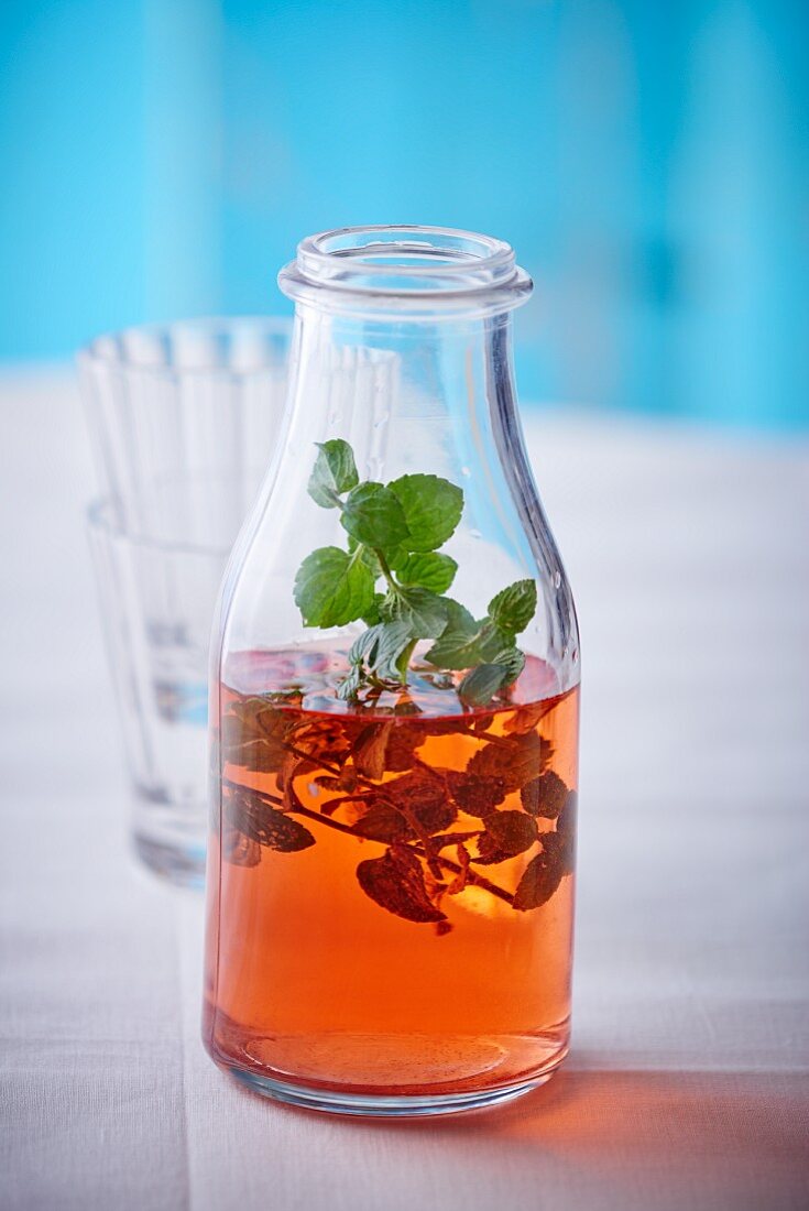 A bottle of strawberry syrup with mint