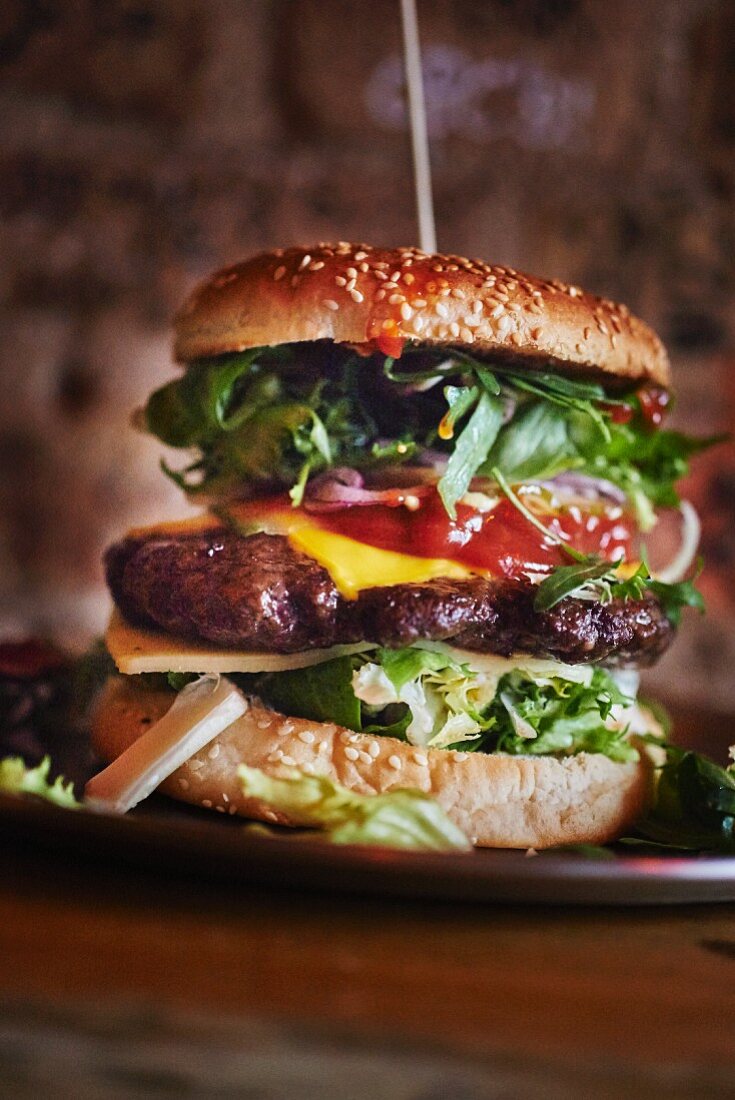 A cheeseburger with ketchup and salad