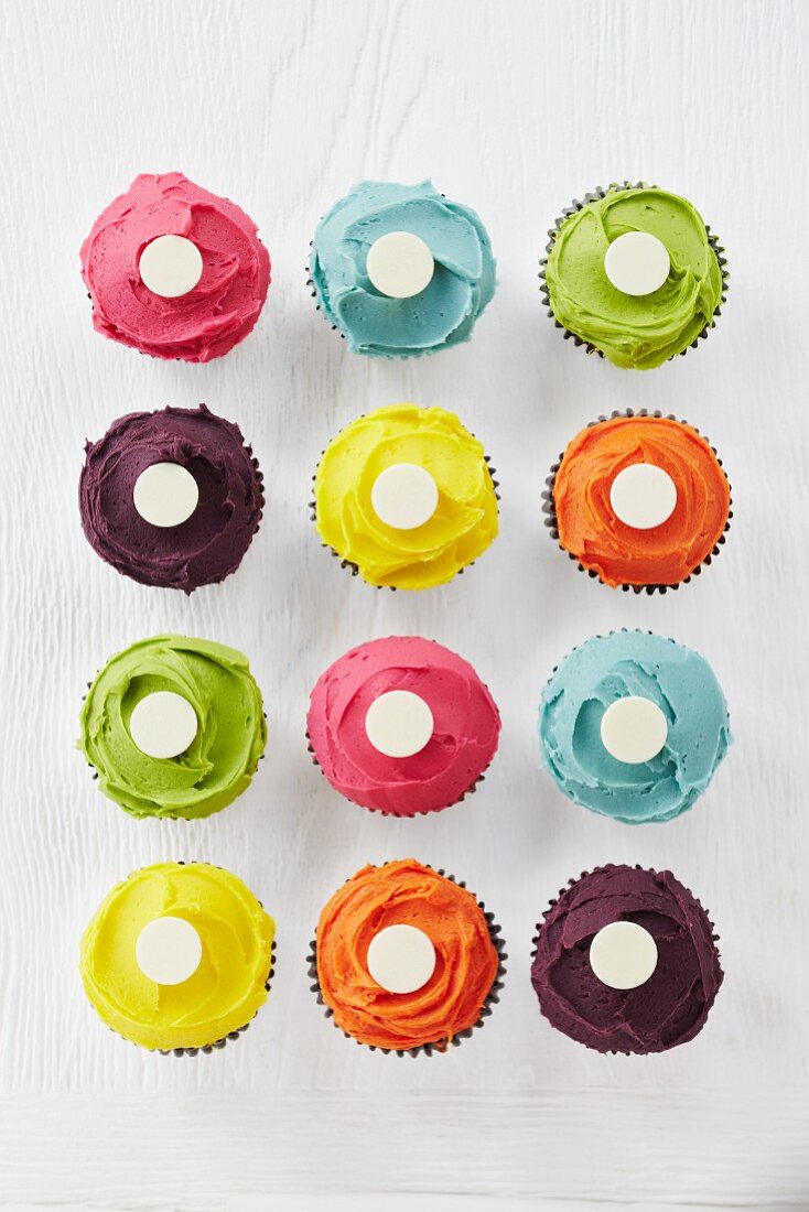 Cupcakes with vibrant icing topped with a white button in the centre (seen from above)