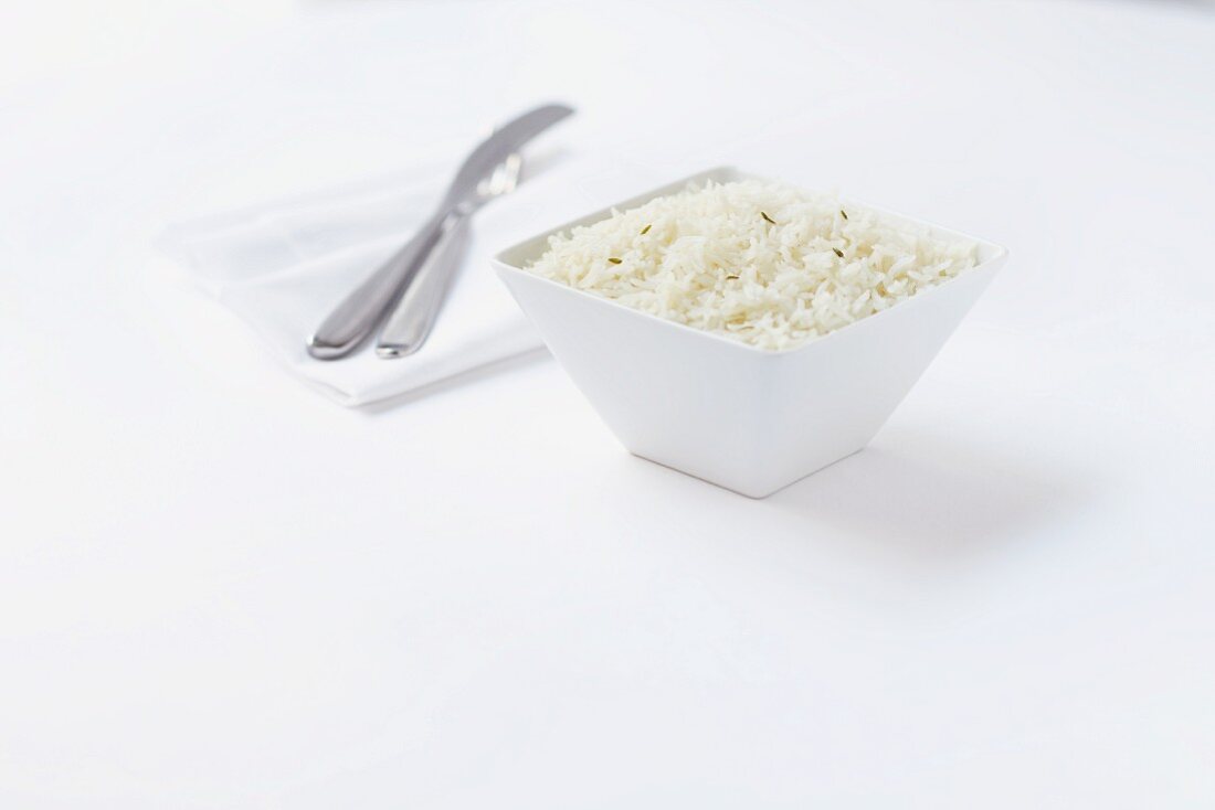 Eine Schüssel Reis, daneben Besteck und Serviette