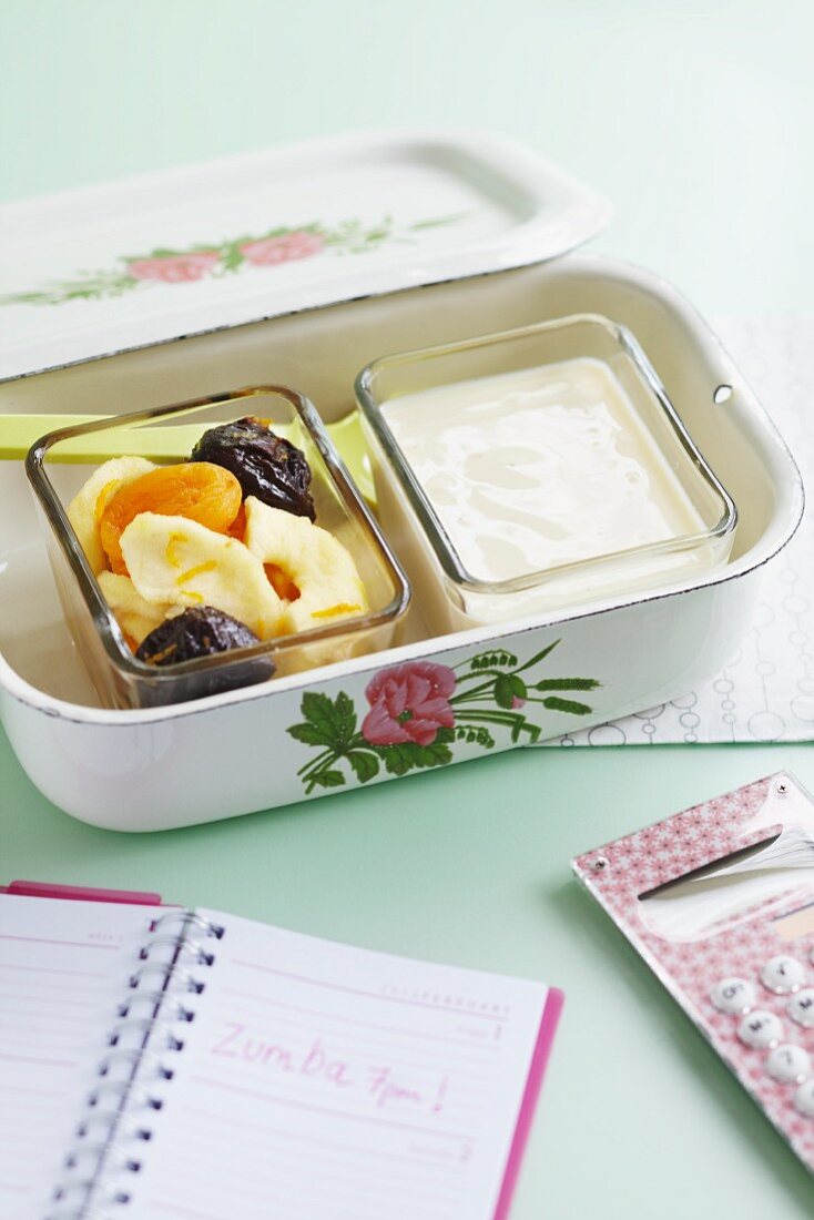 Joghurt mit getrockneten Aprikosen, Bananen und Pflaumen in einer Lunchbox