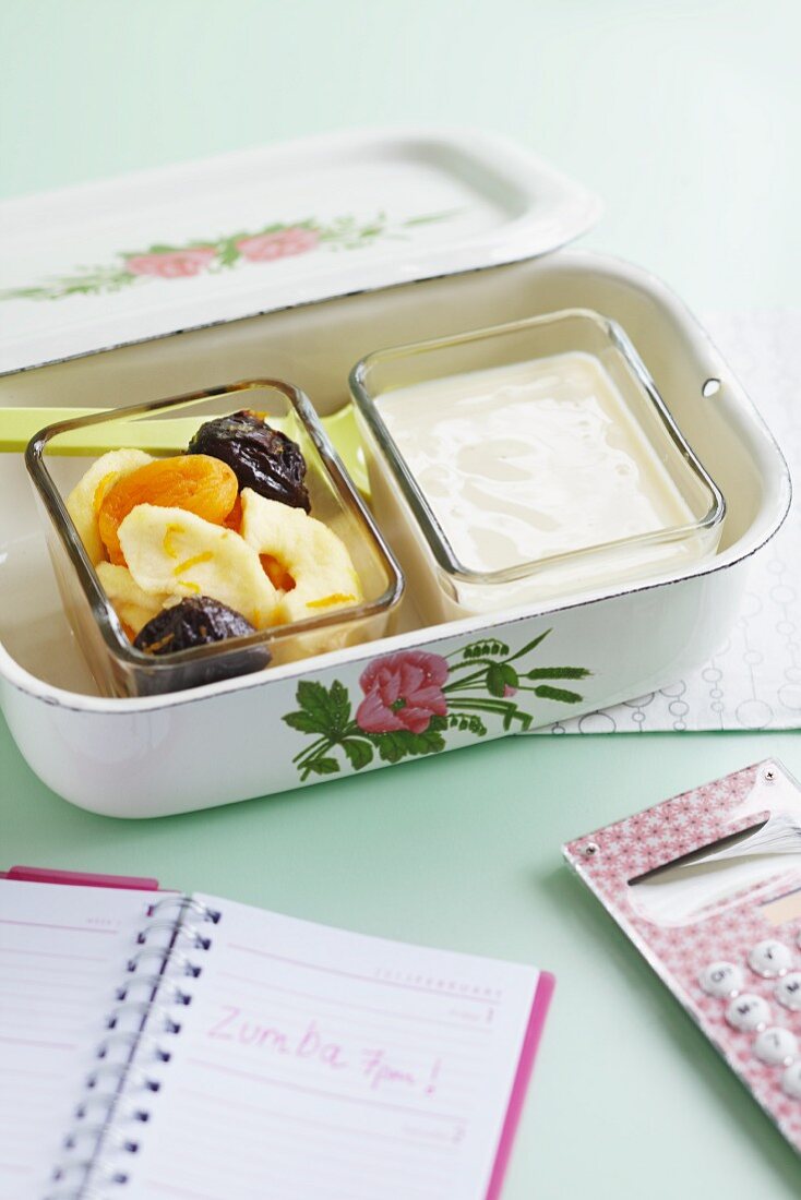 Yoghurt with dried apricots, bananas and plums in a lunch box